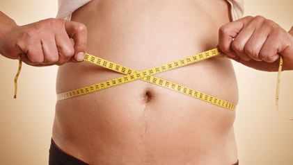 Viszeralfett: Foto von einem Mann der seinen dicken Bauch mit einem Maßband vermisst