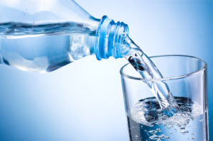 Wasserdiät: Foto von einer Flasche Wasser die Inhalt in ein Glas schüttet