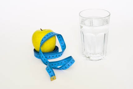  Wasserdiät: Foto von einem Apfel mit Maßband und einem Wasserglas