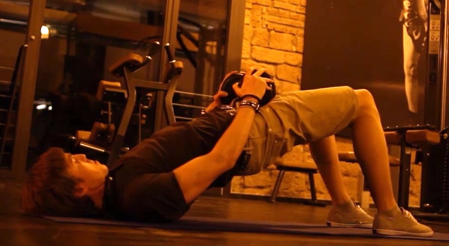 Rückenübungen Muskelaufbau: Foto von einem Mann bei der Rücken-Übung Beckenheben mit Kurzhantel.
