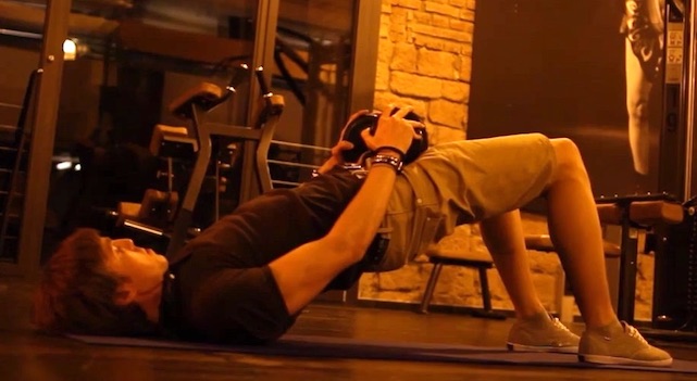 Rundrücken wegtrainieren: Foto von einem Mann bei der Rücken-Übung Beckenheben mit Kurzhantel.